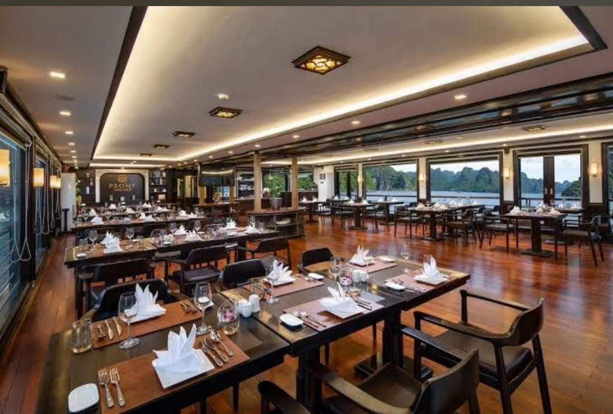 Restaurant laid for dinner, tables down both sides and windows onto the water the length of the room