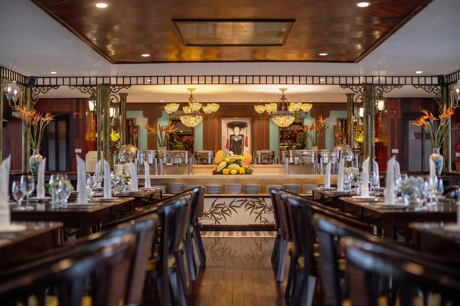 Main restaurant seen down its length, long tables laid and a carved ceiling running overhead