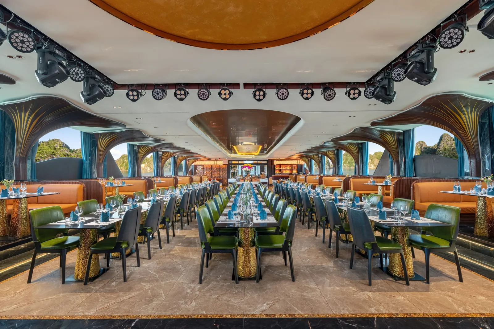 Main restaurant seen down its length, two rows of green and orange chairs under a vaulted patterned ceiling