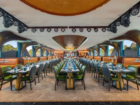 Main restaurant seen down its length, two rows of green and orange chairs under a vaulted patterned ceiling