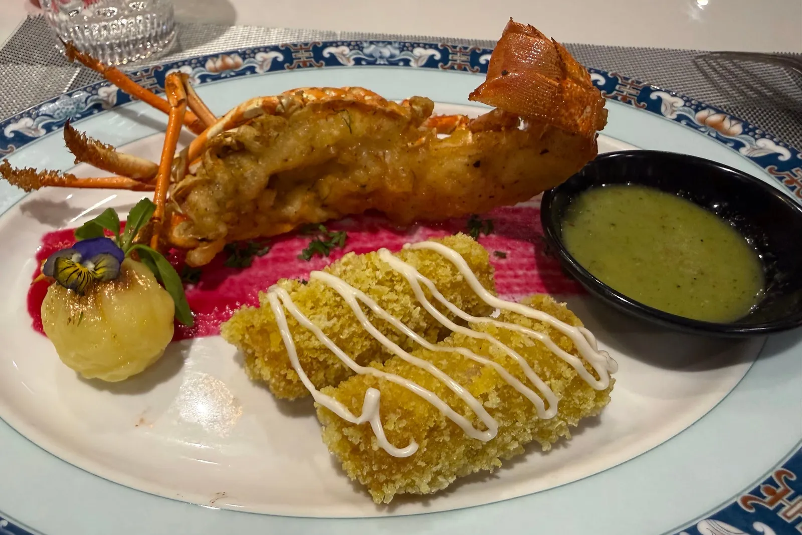 Half a lobster plated with saffron rice and a dipping sauce