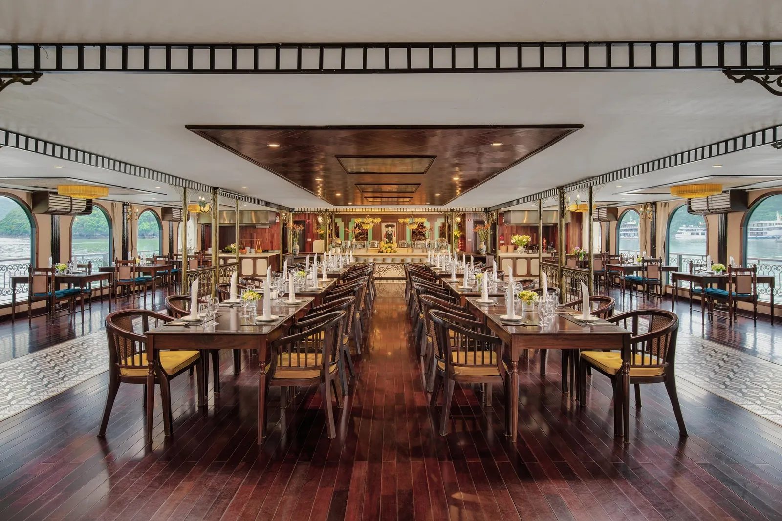 Dining room with round tables and arched windows down both sides, the bay showing through