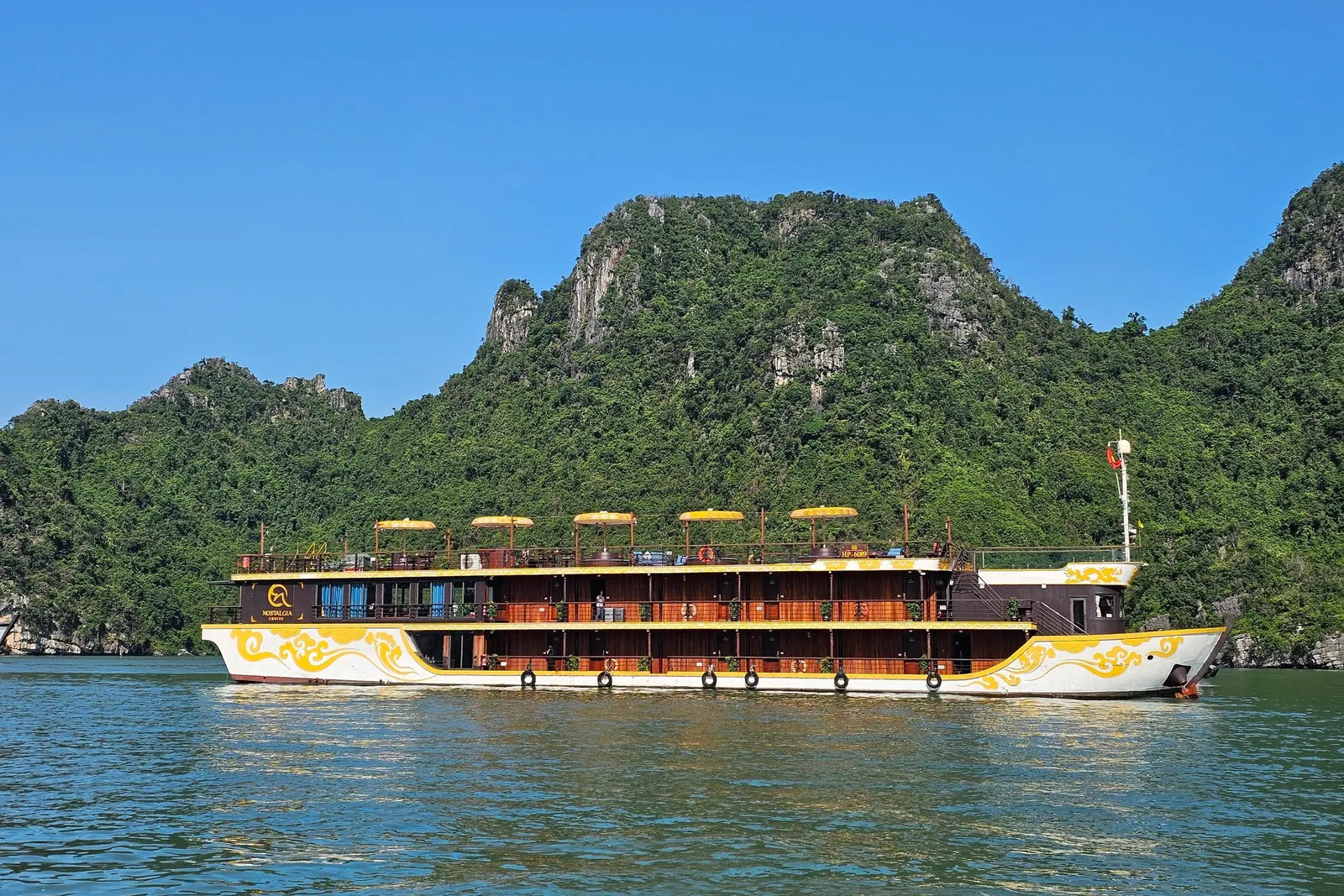 Nostalgia side on under way, cream and gold hull with a row of yellow parasols along the top deck
