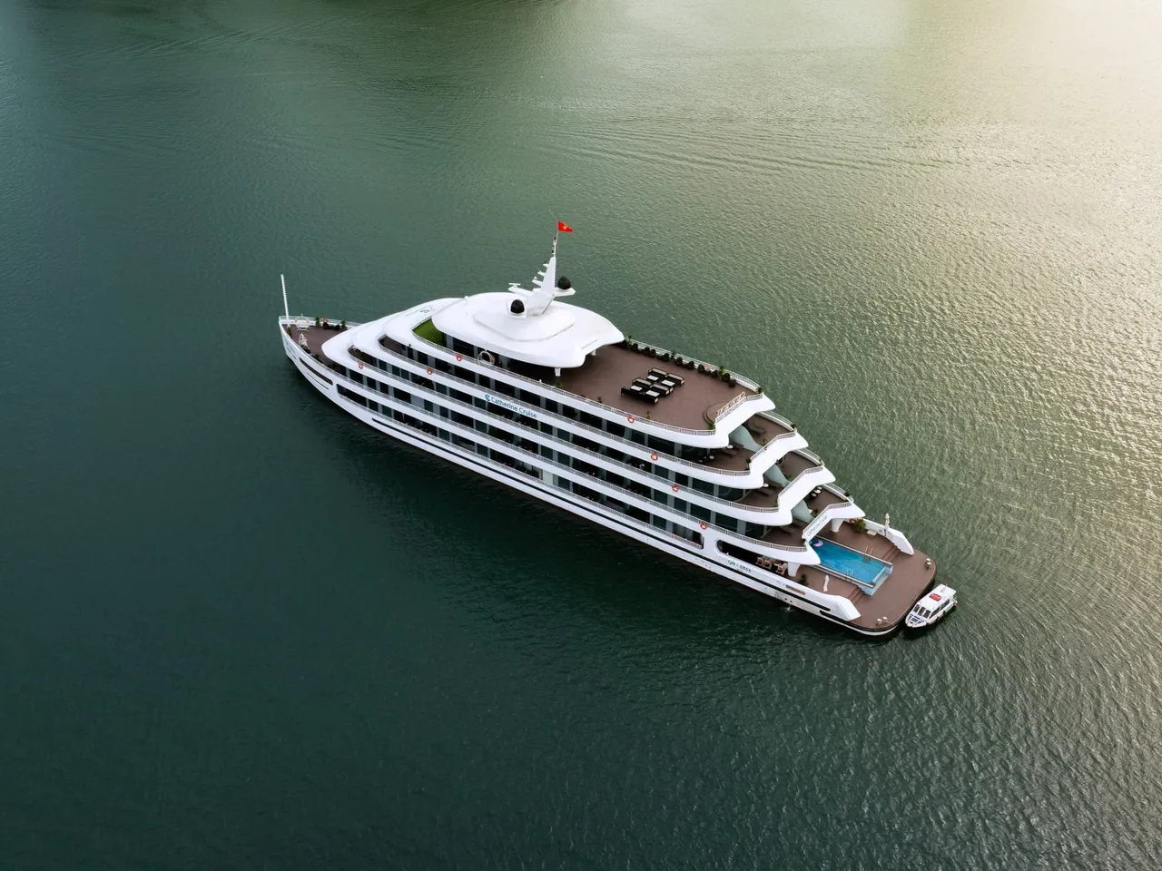 Catherine seen straight down from the air, five white decks and a pool on the stern, alone on olive-green water