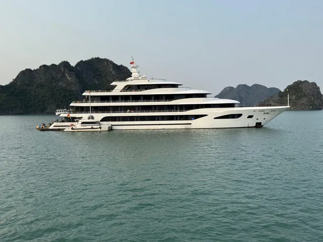Scarlet Pearl at anchor, a long white hull with four decks set against a wall of karst