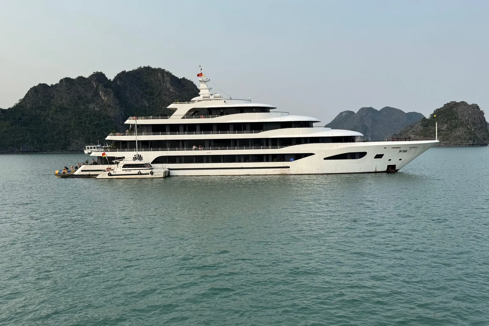 Scarlet Pearl at anchor, a long white hull with four decks set against a wall of karst