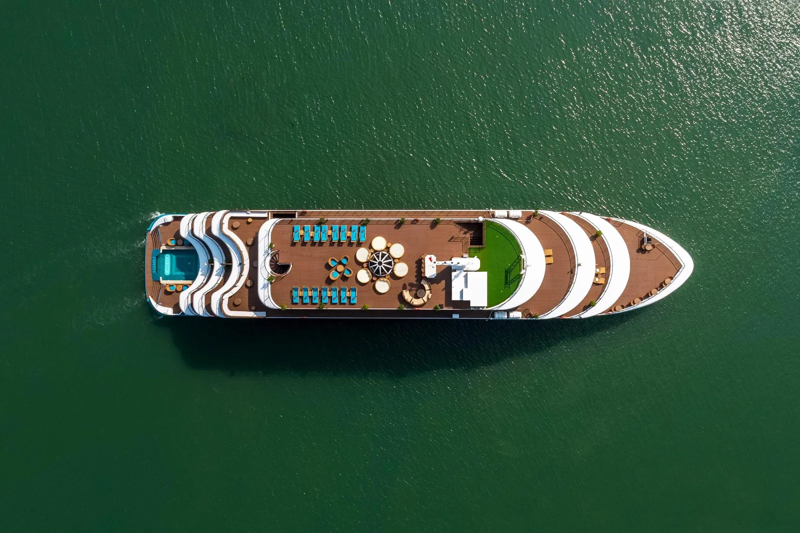 Capella seen straight down from the air, the whole white hull and its stern pool laid out on flat green water