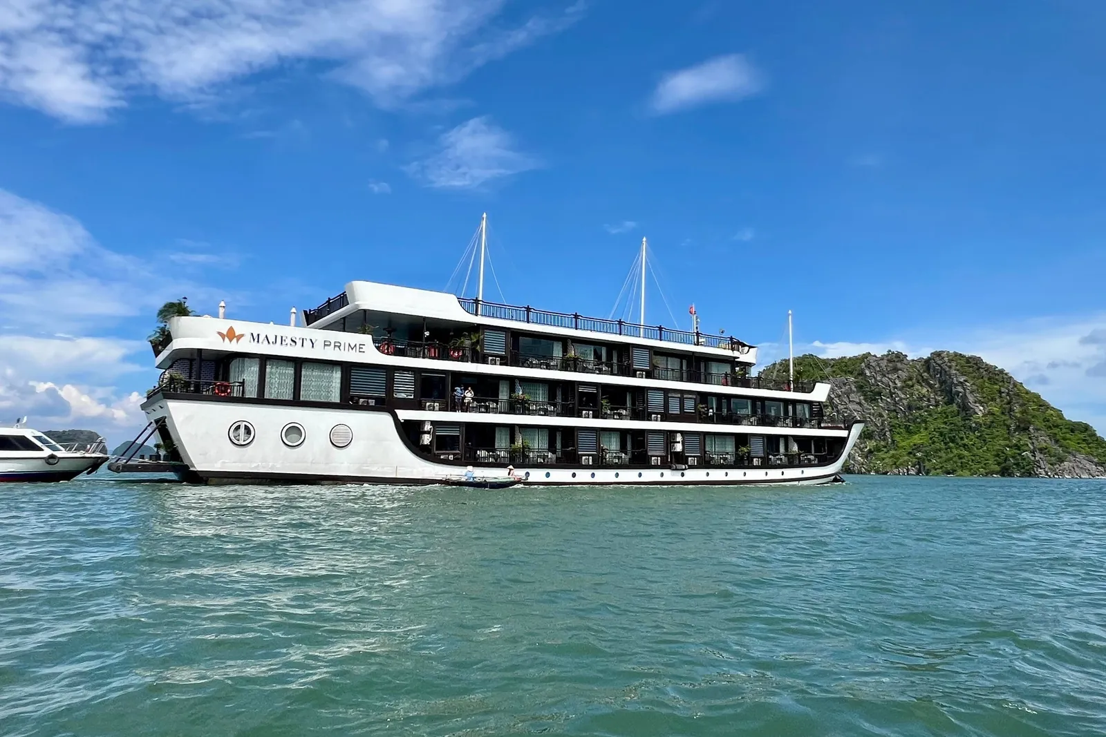 Majesty Prime broadside on turquoise water, the ship name on a white hull below three decks of windows