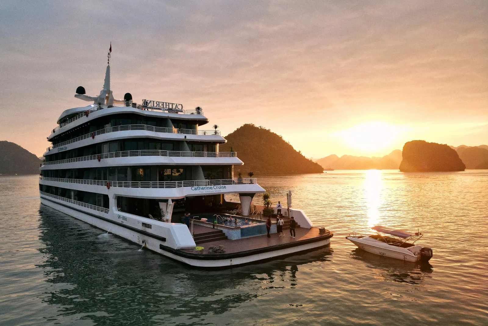 Catherine at sunset from the air, a tender alongside and the sun low over the karst islands behind
