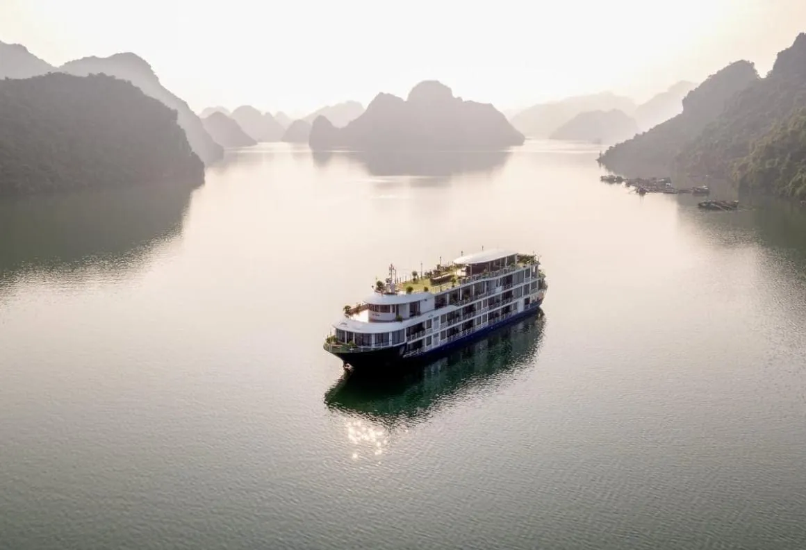 Mon Chéri alone on silver water in flat morning light, karst islands fading back into haze