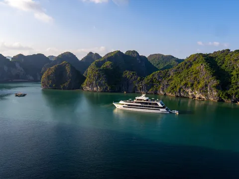 Stellar of the Seas seen from a clifftop, alone on green water in a bowl of karst islands