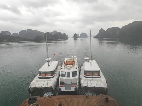 Three tenders moored side by side at the stern, seen from the deck above on a grey morning