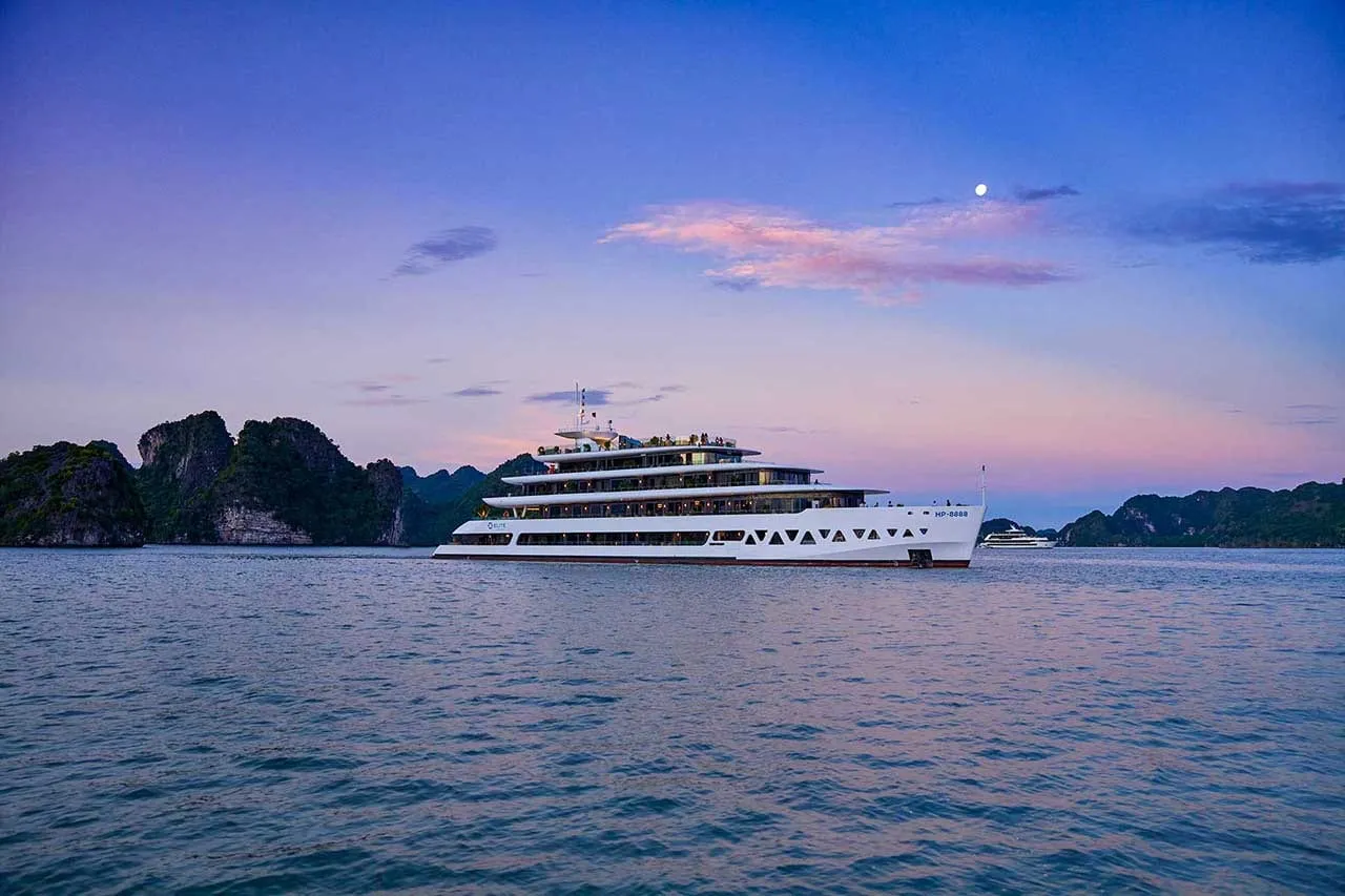 Elite of the Seas broadside at dusk, a long white hull under a pink and blue sky