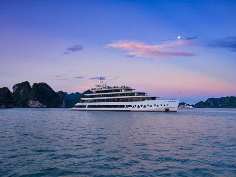 Elite of the Seas broadside at dusk, a long white hull under a pink and blue sky