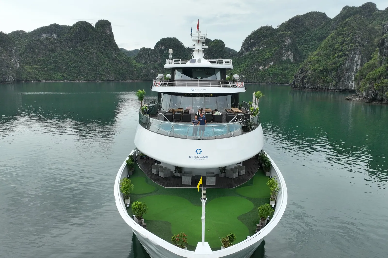 Head on view of the bow, the foredeck laid with green matting and karst rising either side
