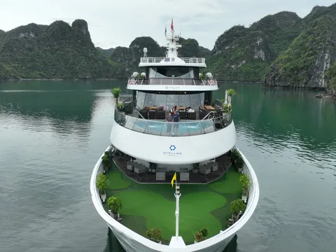 Head on view of the bow, the foredeck laid with green matting and karst rising either side
