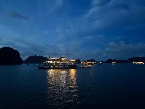 Nostalgia lit up after dark, her lights laid out in a long reflection across black water