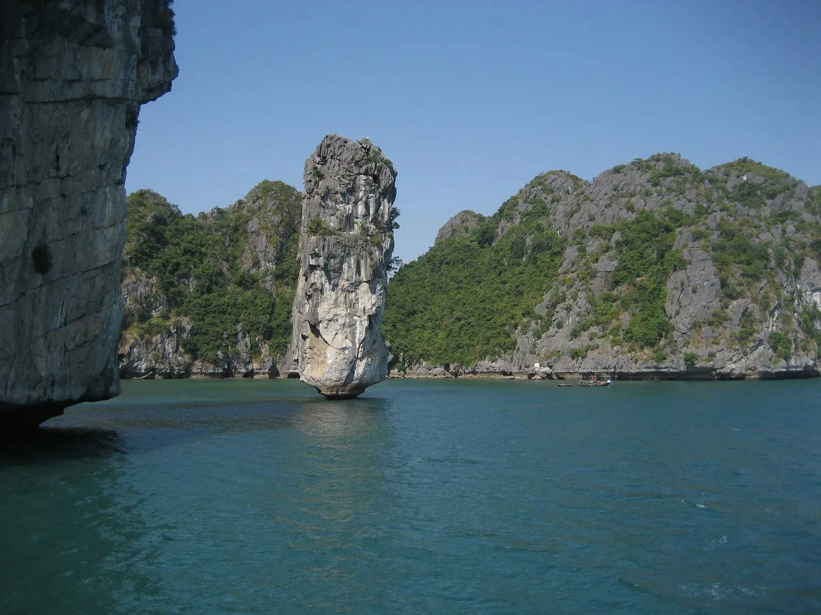 A tall pillar of rock beside limestone islands in Ha Long Bay