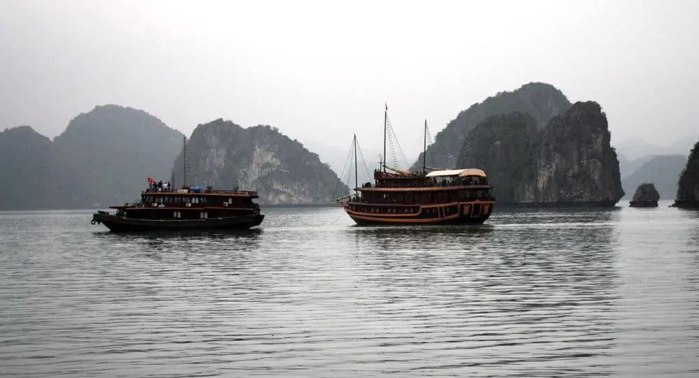 Two wooden boats on the water beneath limestone islands