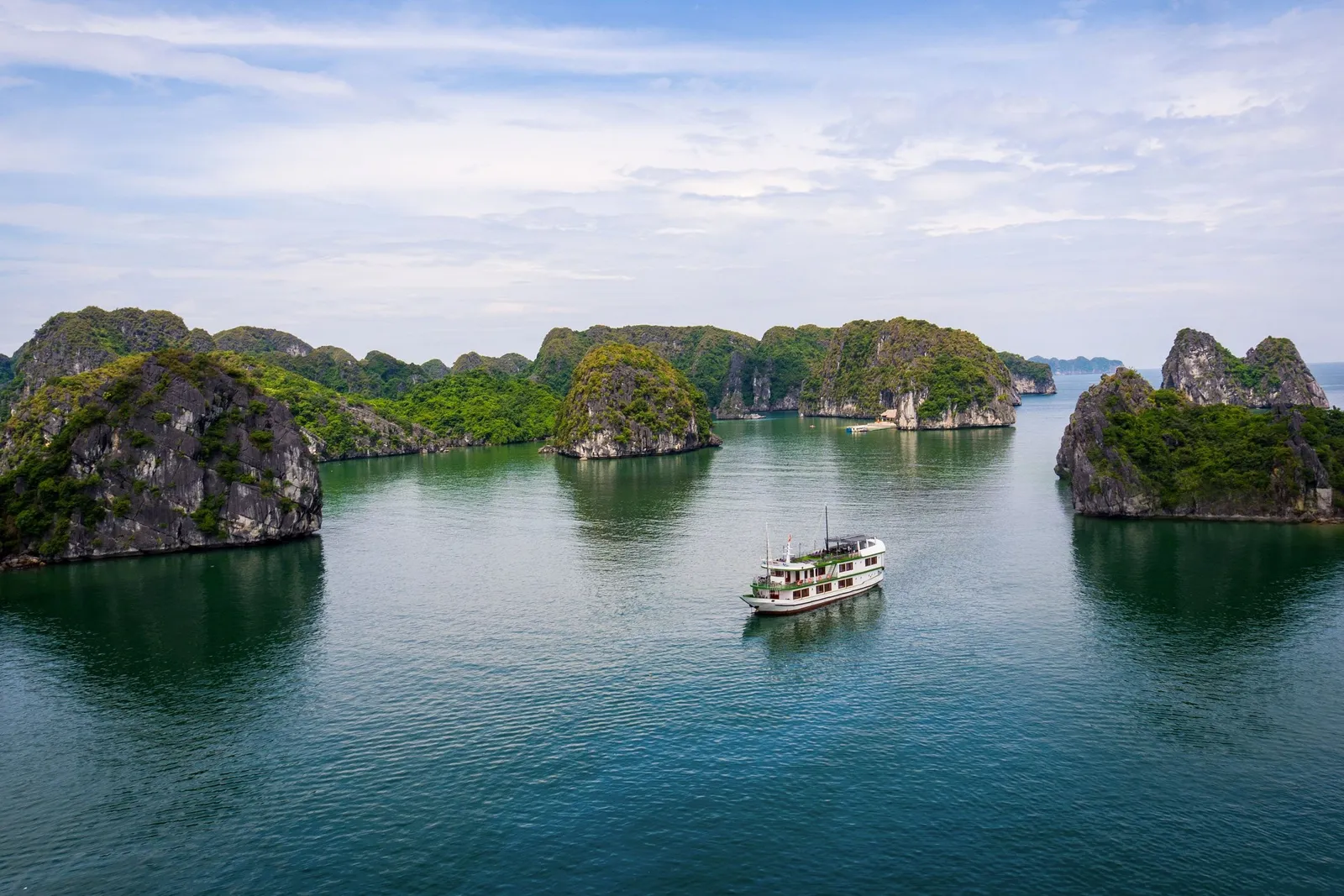 Venezia cruise boat, white with green trim, anchored among the limestone islands of Lan Ha Bay