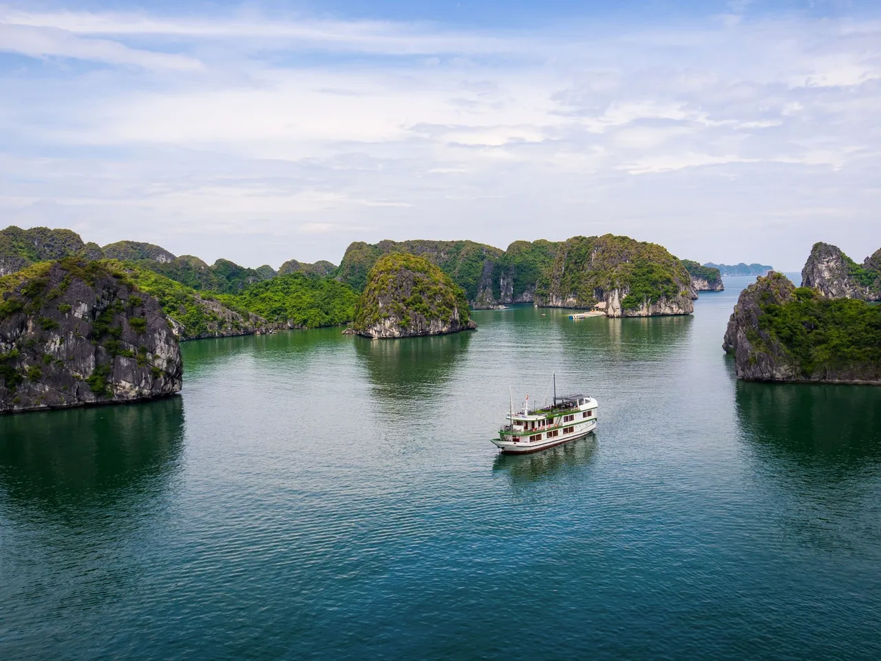 Venezia cruise boat, white with green trim, anchored among the limestone islands of Lan Ha Bay