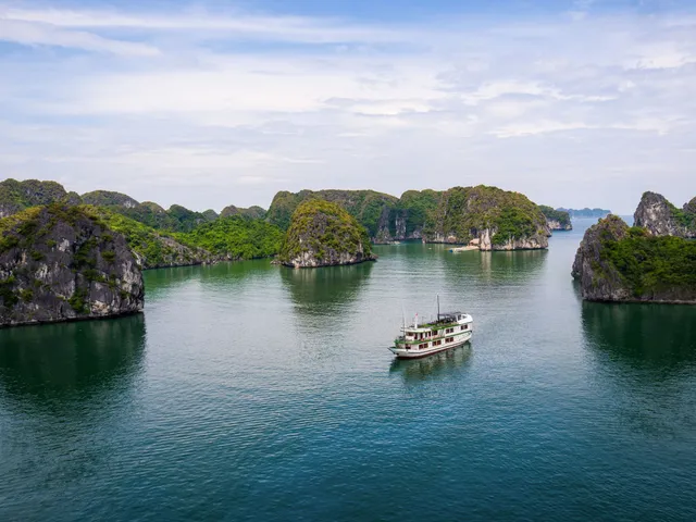 Venezia cruise boat, white with green trim, anchored among the limestone islands of Lan Ha Bay