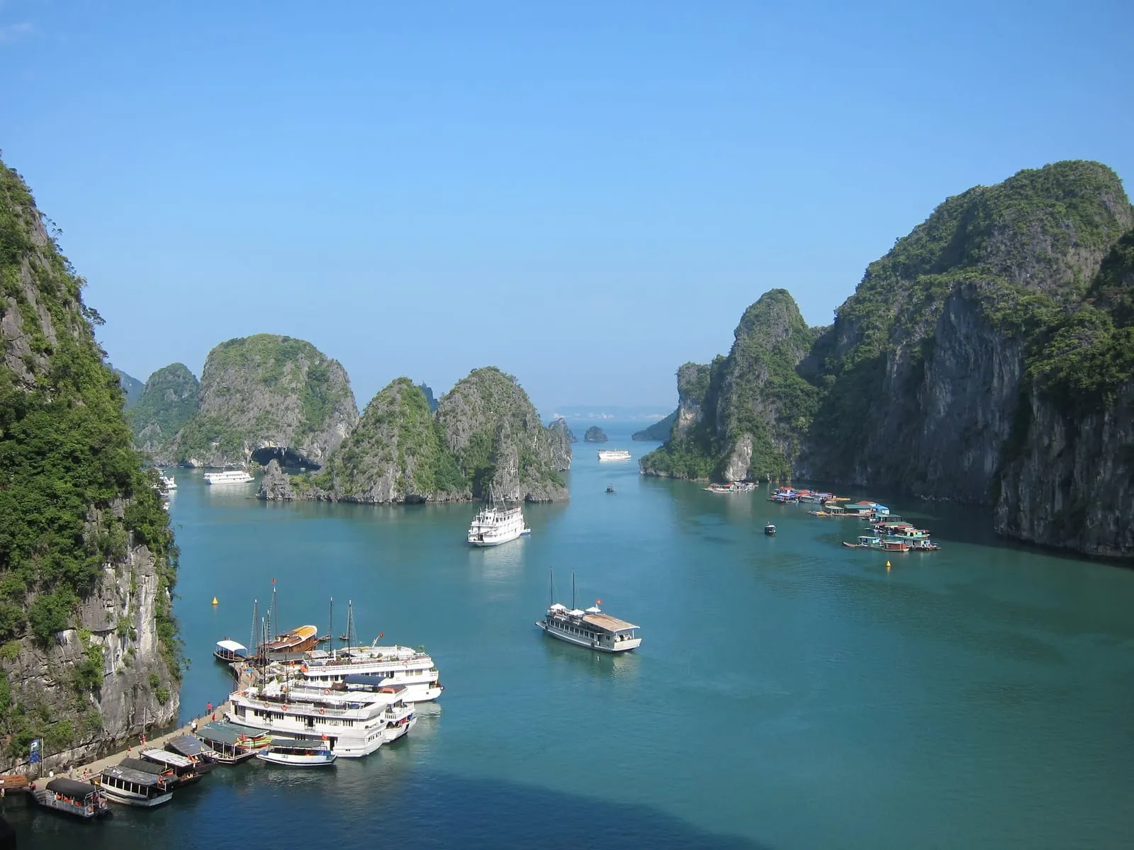 Cruise boats moored beside limestone cliffs, with more islands behind